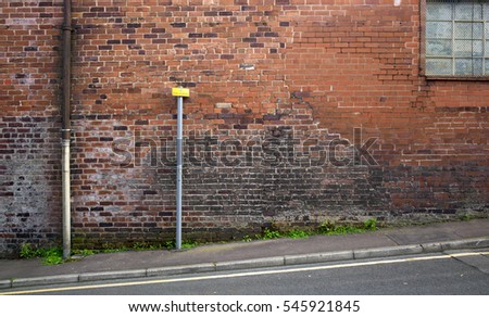 Cracked brickwork on factory building with parking restriction notice, Burnley, UK