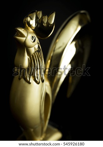 Golden rooster figurine close-up on a black background.