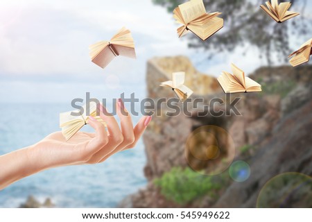 Female hand and flying books on landscape background