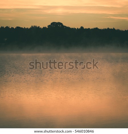 Foggy morning on the country lake with colorful sky and clouds - instant vintage square photo