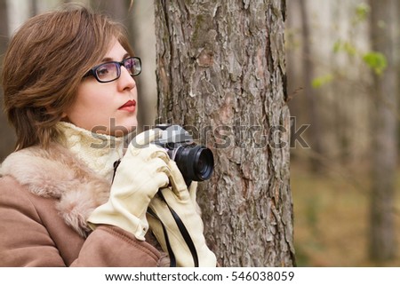 elegant young woman taking photo in the forest