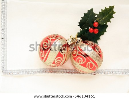 red and gold Christmas Balls with holly leaves on a white and silver napkin/Christmas napkin/Christmas table setting