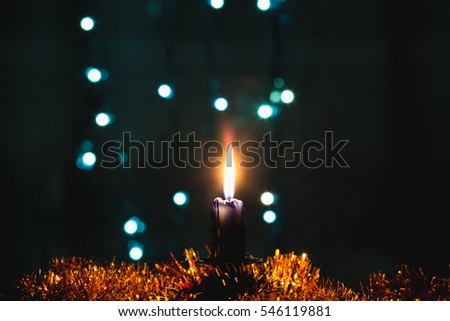 Candle standing on the table in the background blurred decorated room with Christmas tree and fireplace. Soft focus