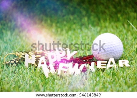 Golf ball with a little present on green grass with Happy New Year lettering and special effect.