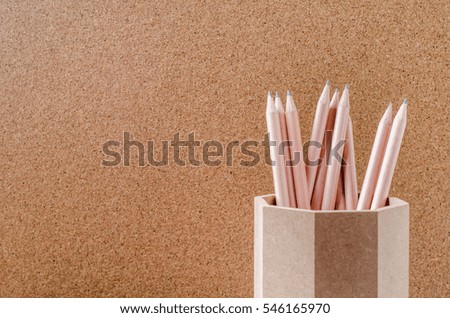 Close up of pencils in wooden holder with brown background