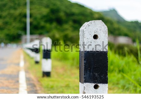 Black and white milestones aligned. Green mountain is in the background. Milestones are representative of success in the past and goal for the future in this year. Royalty-Free Stock Photo #546193525