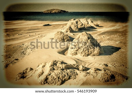 View of a small island from the Israeli shore of the Mediterranean Sea. Sand blowing over beach dune in wind in Israel. Vintage Style Toned Picture