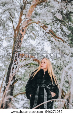 portrait of a girl with her long blonde hair in the snowy forest. Effect Retro photo, grain