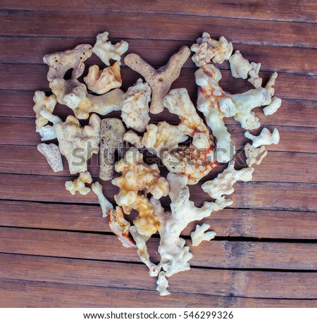 Heart from white corals on wooden background. Seashore love decor from beach finding. Multicolored ornament for Valentine Day greeting. Nature care heart seaside decor. Marine heart on grungy backdrop