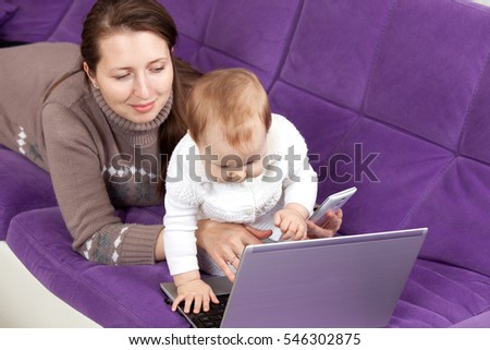 young woman with a child working at a laptop