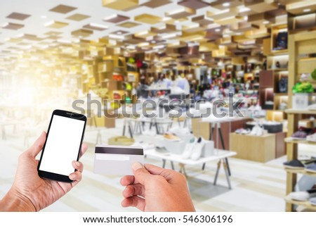 Hand Hold Smart phone with Credit Card over blurred of Shopping mall.