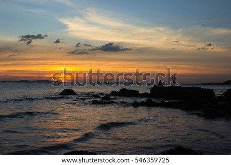 Silhouette of loving couple on the rock and the beach with island during sunrise