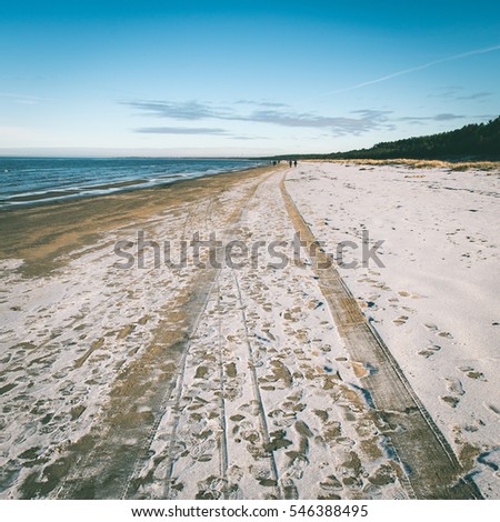 frozen sea beach with blue sky and snow covered tracks - instant vintage square photo