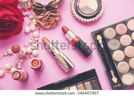 Makeup Compact Cosmetics set for beautiful woman who love make up with red rose and pearl on pink background. colorful lipstick, brush on, eye shadow palette.  Beauty fashion concept.