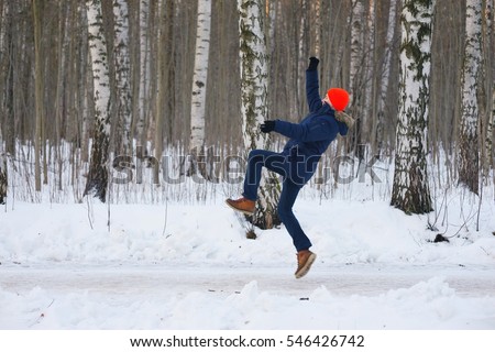 Young modern man slipped his body lost balance during walk go from birch grove in winter town. Freeze frame while jumping out and waving hands up before falling over snow. side skid boot has hazard. Royalty-Free Stock Photo #546426742