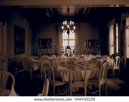 sepia picture of a dining room prepared for many guests with a chandelier in the middle