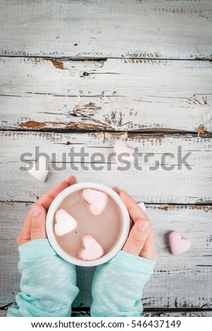 Girl drinking hot chocolate with marshmallows in the shape of hearts, Valentine's Day celebration, hands in the picture, top view, copy space