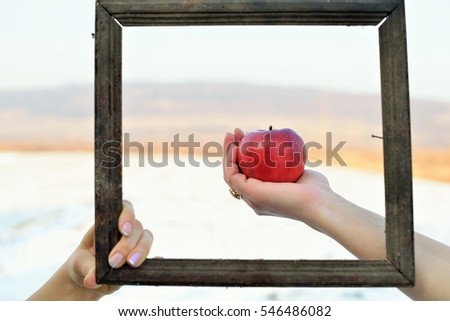 3d picture in nature. A red apple in one hand and an old frame