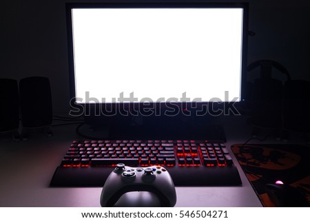 Custom built gaming computer with white screen, keyboard, mouse, desktop, components, hardware, gaming chair under low light. Selective focus.