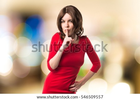 Brunette woman making silence gesture on unfocused background