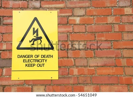 high voltage danger yellow sign on a brick wall building