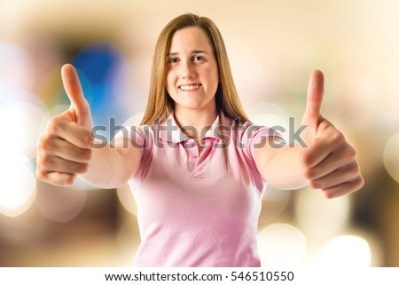 Young girl making Ok sign on unfocused background