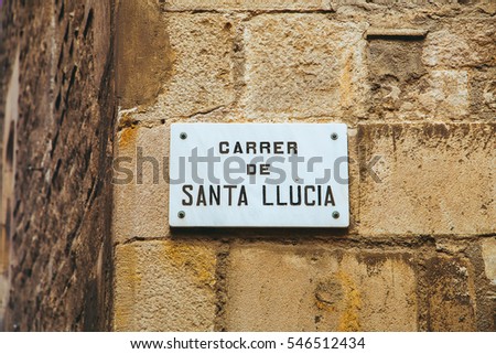 Ceramic sign with the writing "Santa Lucia" hanging on a wall along the streets of Barcelona, Spain.