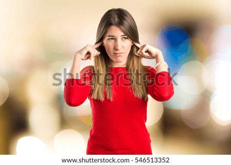 Cute girl covering her ears on unfocused background