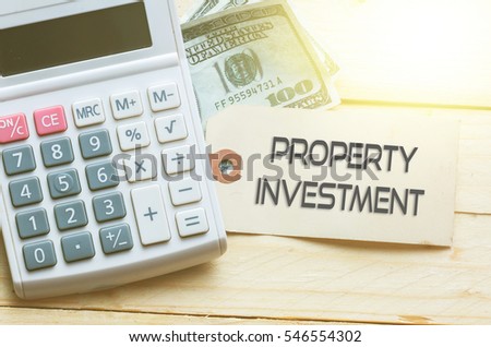 PROPERTY INVESTMENT words on tag with dollar note and calculator on wood backgroud,Finance Concept