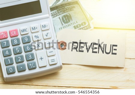 REVENUE Words on tag with dollar note and calculator on wood backgroud,Finance Concept