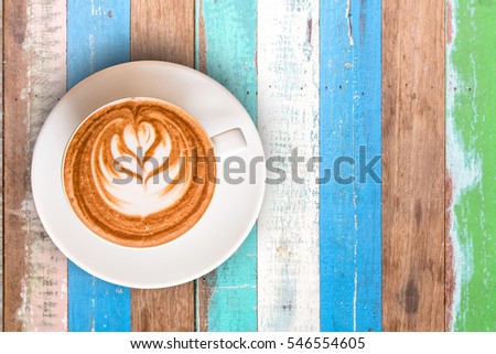 Top view hot Latte Coffee in cup on Wooden table multi color textured for background.