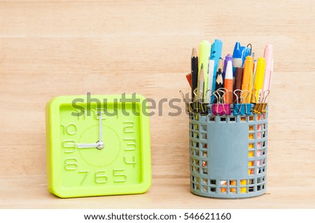 Green clock and Office stationary on wooden table.