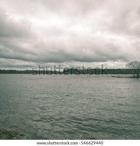 dramatic clouds over the river in misty morning in spring with reflections in water - instant vintage square photo