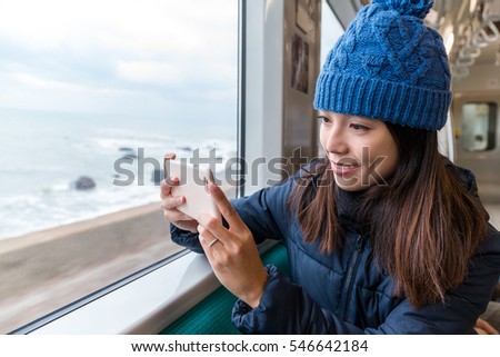 Woman taking photo by mobile phone at train