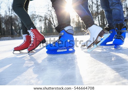 Closeup of legs in skates on ice rink.  Friends skating together outdoors  at winter frozen lake