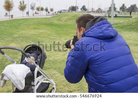 Father take photograph of his child in baby pram. Cold Winter Day