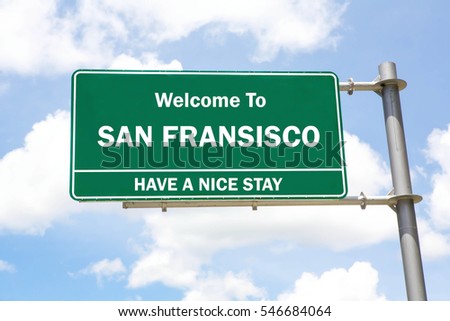 Green overhead road sign with a Welcome to San Fransisco, Have a Nice Stay concept against a partly cloudy sky background.