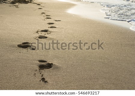 Footprints on the gold sand at sunset