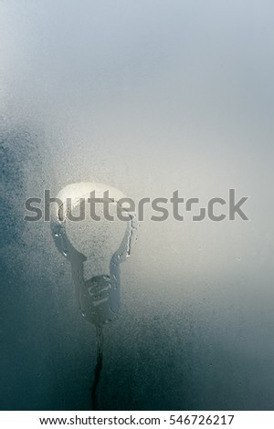Abstract blurry background of foggy window with light bulb drawing, rainy season.