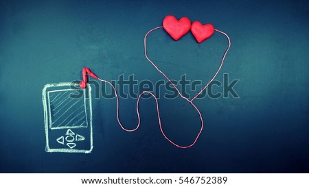two clay heart are listening to the song via small talk connect to music device on old dirty shiny blackboard. in love couple, valentine or wedding theme, vintage  background Royalty-Free Stock Photo #546752389