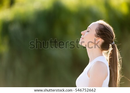 Portrait of beautiful smiling young woman enjoying yoga, relaxing, feeling alive, breathing fresh air, got freedom from work or relations, calm and dreaming with closed eyes, in green park, copy space Royalty-Free Stock Photo #546752662