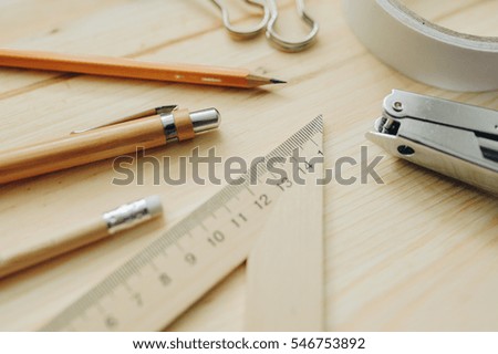 Wood pencil, pen, triangle, briefpapier clips, hefter on the desk in daylight. Office table