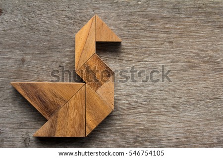 Wooden tangram as bird shape on old wood background