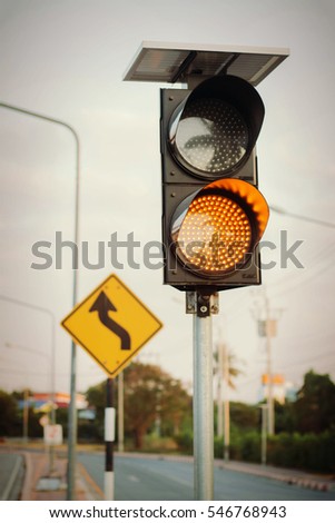 Amber traffic lights at the road crossing and the left and right reverse curve head signs on the background