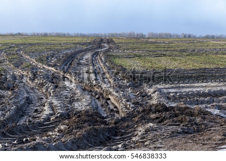  Agricultural field on which drove heavy vehicles. Ruts from the wheels in the mud, formed after the rain. Photo closeup.