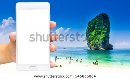Man use mobile phone, blur image of the beach in Thailand as background.