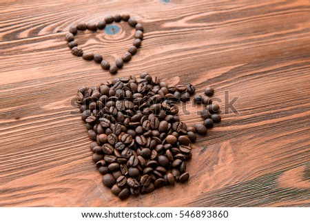Coffee cup made from beans, grain with heart on wooden background. Valentine's Day or Wedding, love, black, frame. Heart shaped Coffee Beans. Coffee beans in shape of cup with heart