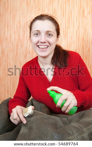 young Woman cleaning a sheepskin with whisk broom at home