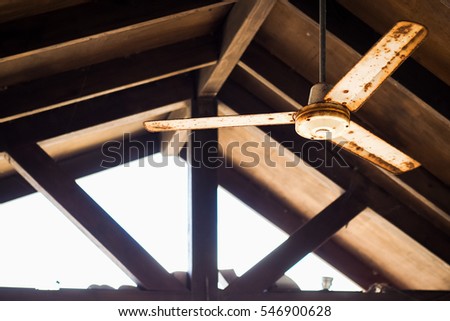 A ceiling fan under a wood pavilion roof