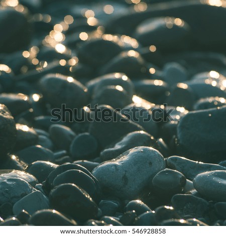 sun reflections on Stones on the beach and sea water in sunset light - instant vintage square photo